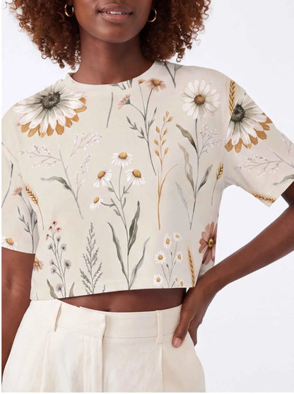 Off-white cropped t-shirt with floral daisy print, short sleeves and round neckline.