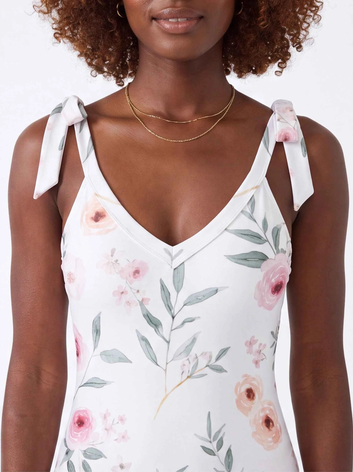 Floral tie-shoulder one-piece swimsuit close-up, white with pink roses and green leaves