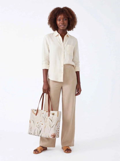 White floral tote bag with brown leather-look handles, structured rectangular silhouette.