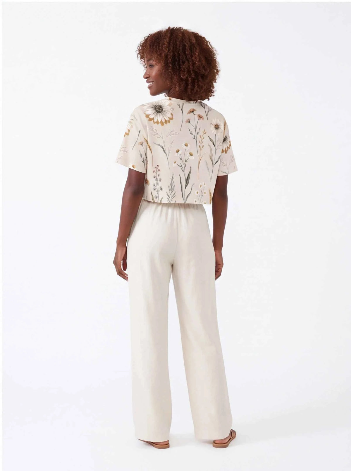 Women’s cropped t-shirt back view: off-white with daisy wildflower print, short sleeves.