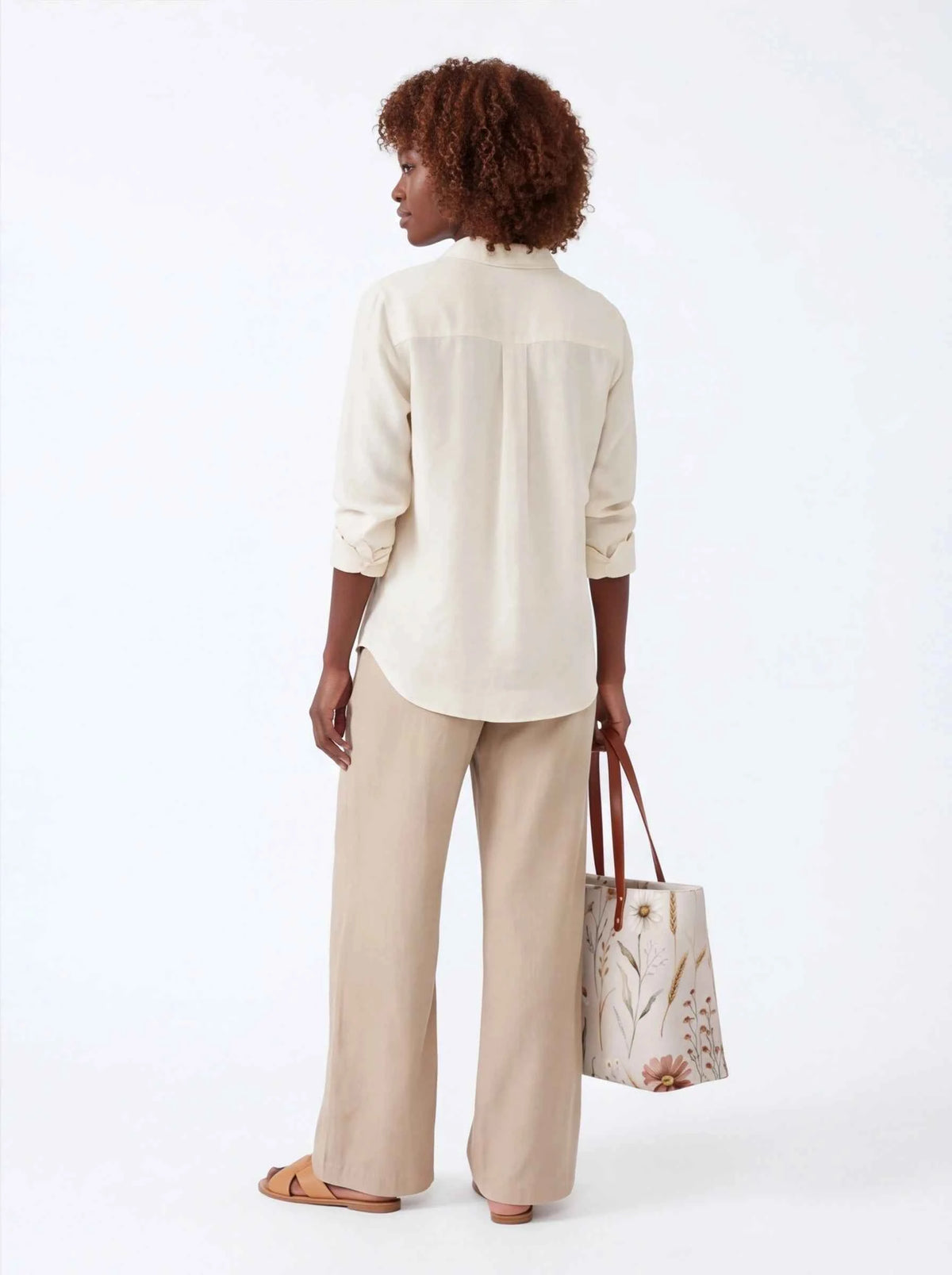 White floral tote bag with brown leather-look handles, side view with top opening.