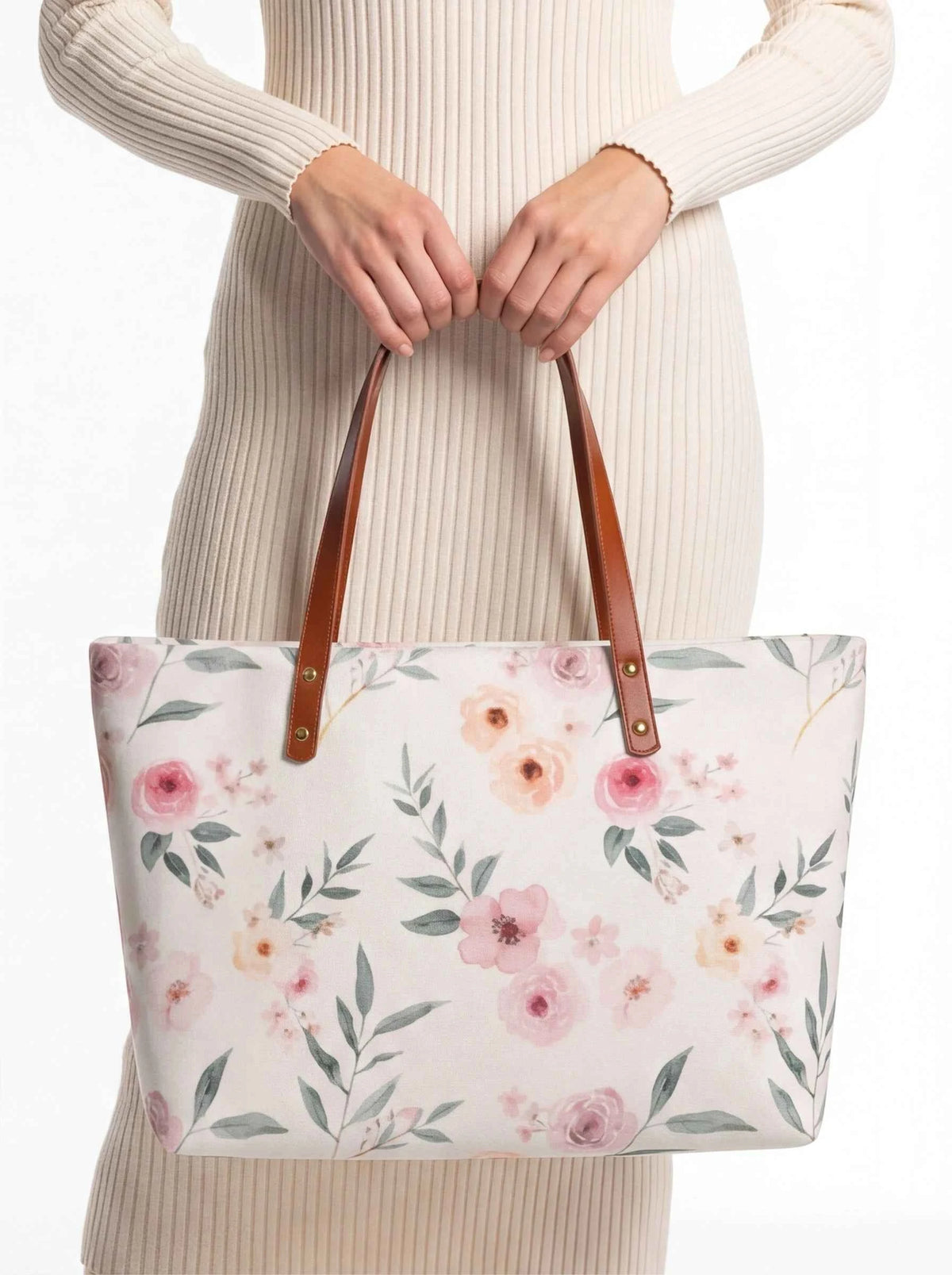 White floral tote bag with brown handles, held by hands