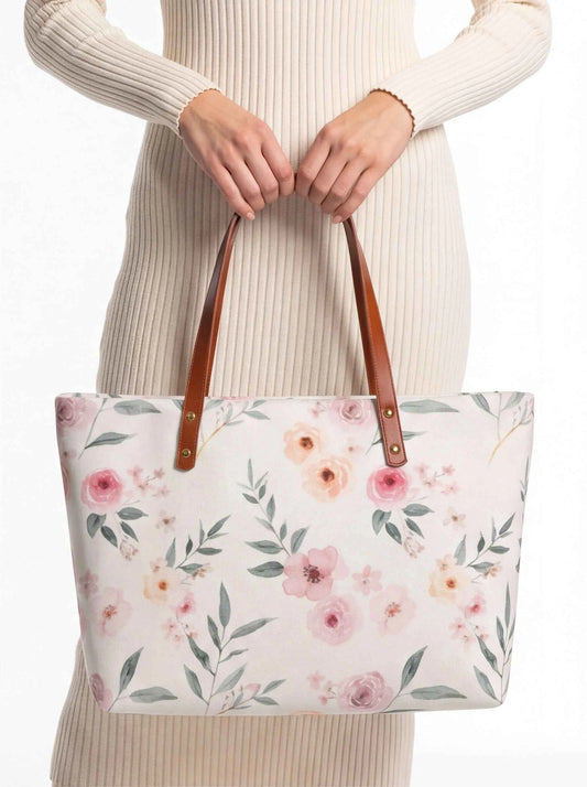 White floral tote bag with brown handles, held by hands