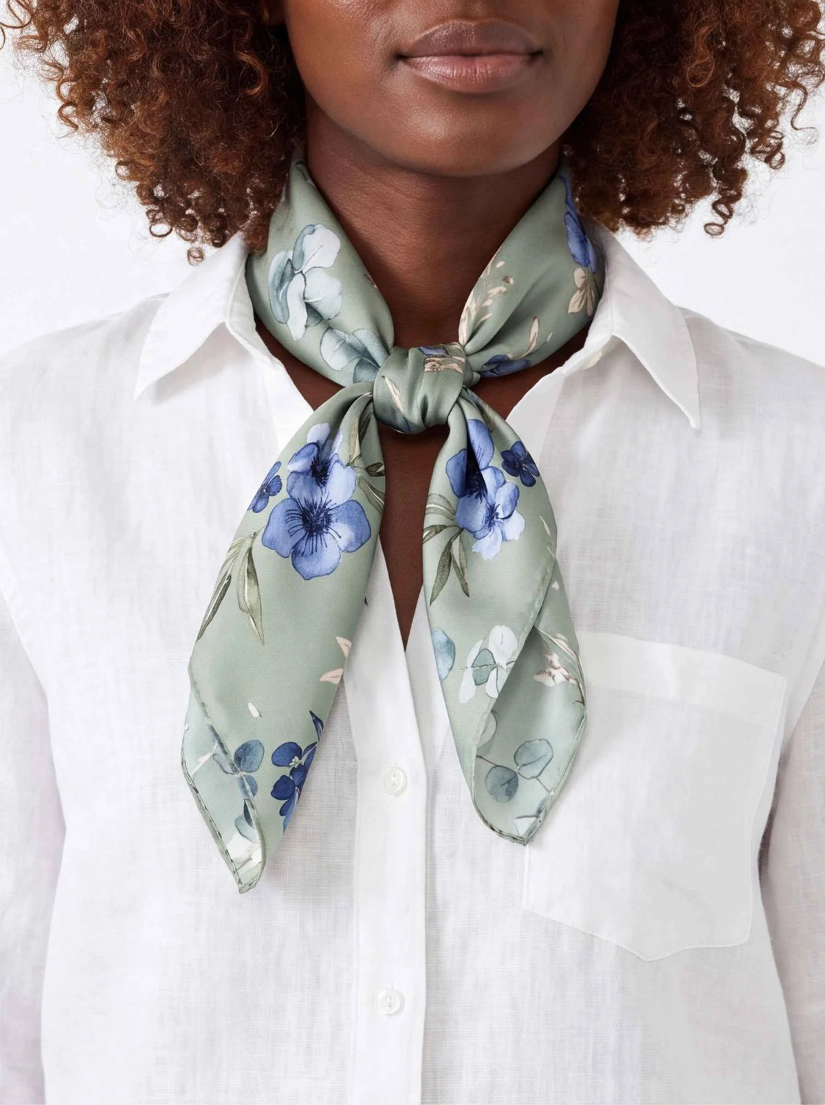 Silk neck scarf with light blue and green floral pattern, tied knot close-up