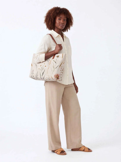 White floral canvas tote bag with brown leather-look handles and spacious interior.