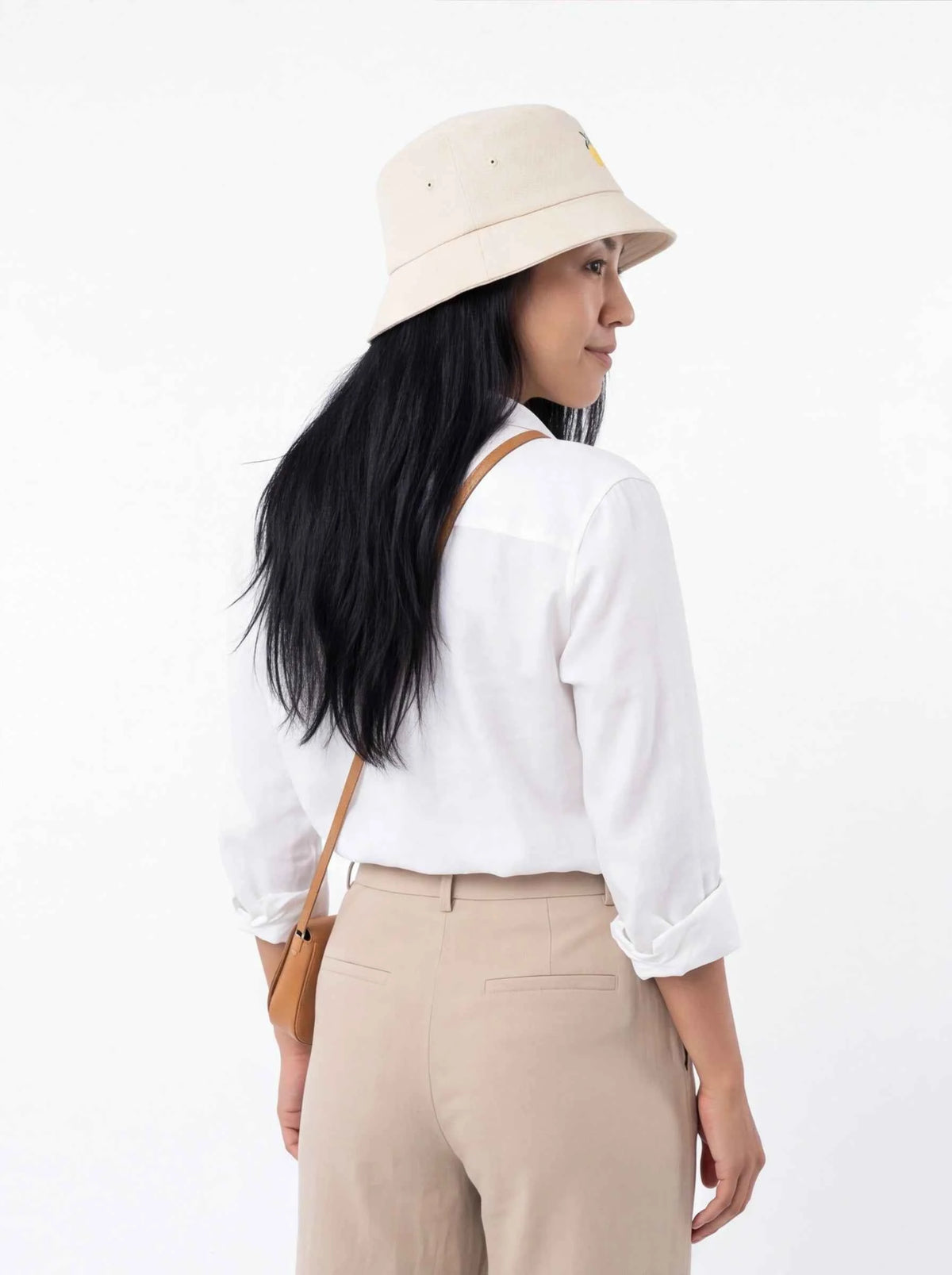 Beige bucket hat with lemon blossom embroidery, worn in side profile