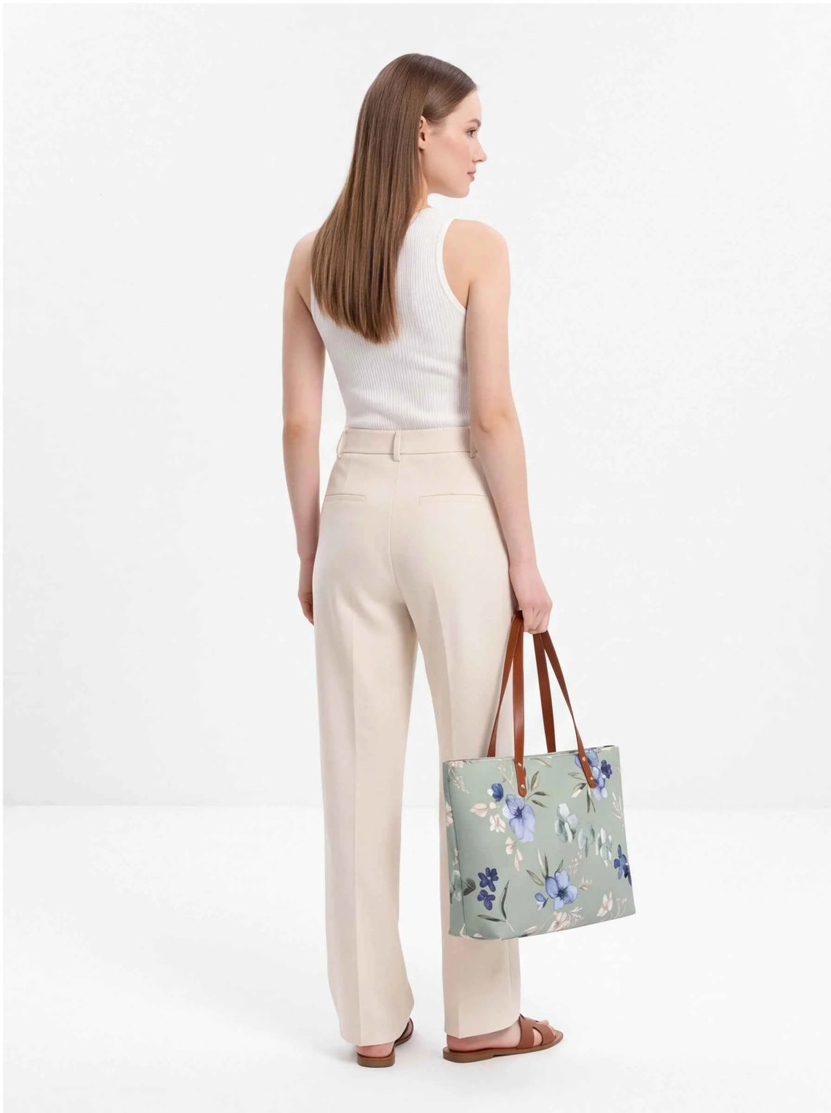 Floral beach tote with brown handles carried at the side, side view