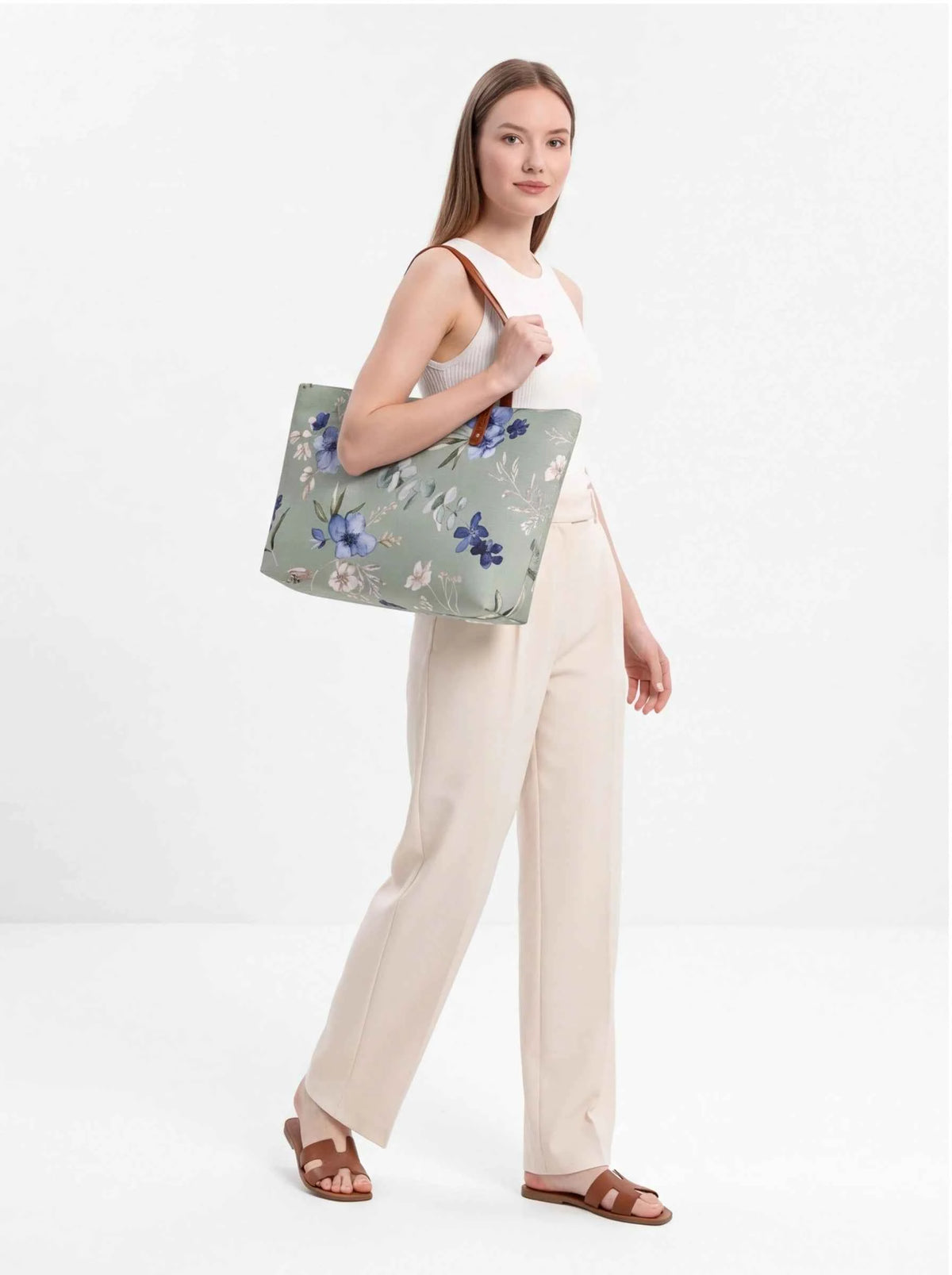 Floral beach tote with brown handles held forward by model