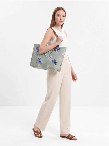 Floral beach tote with brown handles held forward by model